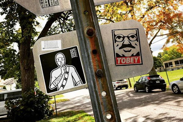Artist Urban Ninja's stickers on a sign
